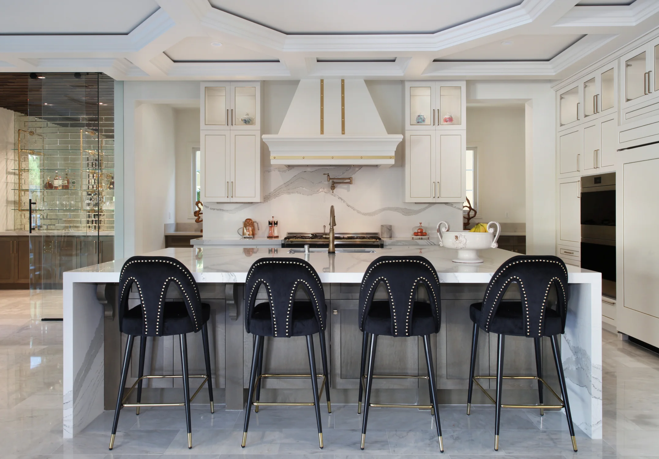 White kitchen with a marble island and four black bar stools