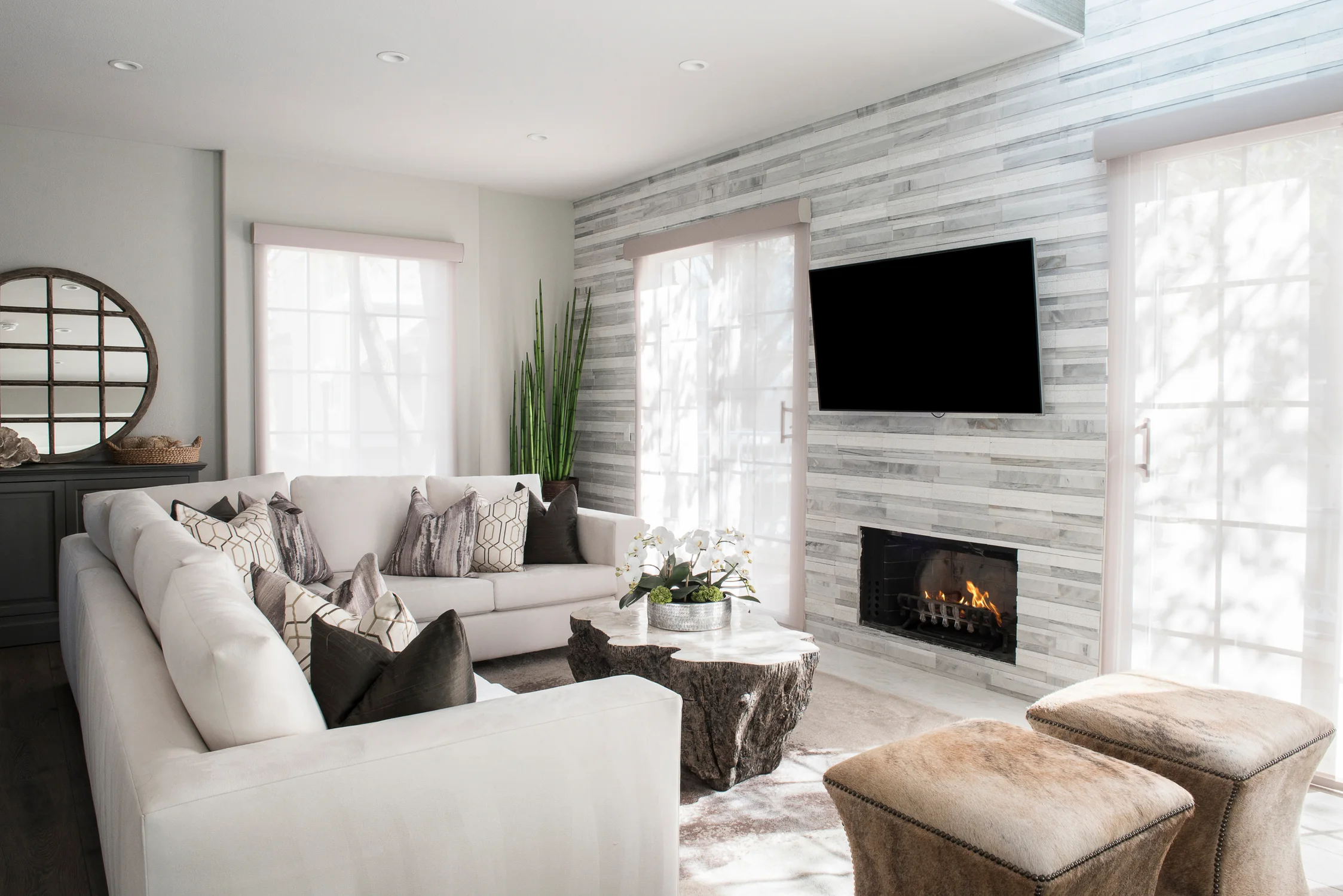 Living room with a white sectional, stone fireplace, and wood coffee table