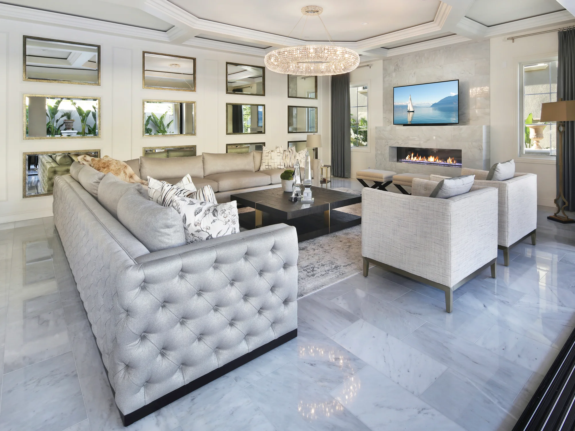 Living room with gray tufted sofas, mirrored wall, and linear fireplace