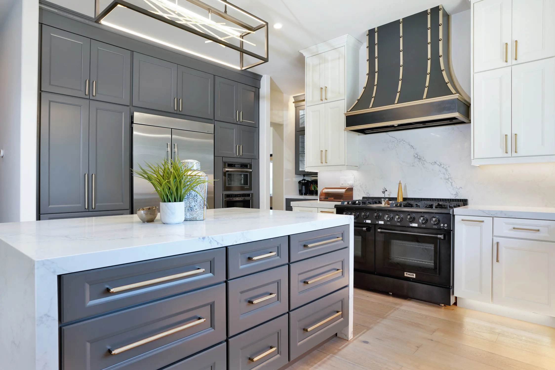 Kitchen with gray cabinetry, marble island, and black range hood