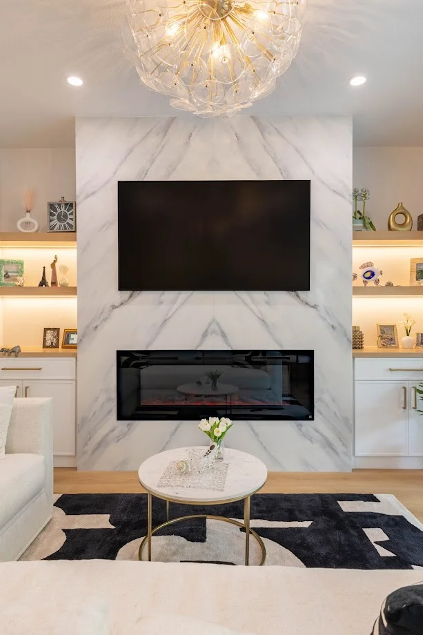 Luxury living room with marble fireplace, chandelier, and built-in shelving